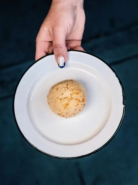 Mano sirviendo un plato blanco con queso dorado
